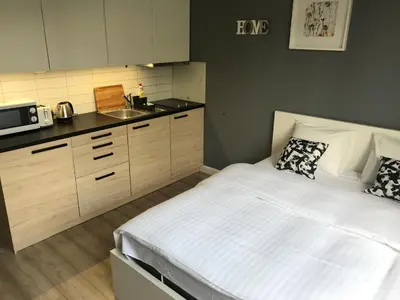 a bedroom with a white bed and a kitchen at Apartment II GrayFor2 Old Town Kraków in Kraków