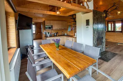 a kitchen and dining room with a wooden table and chairs at Tarnawianka Apart, jacuzzi, sauna, bilard in Tarnawa Górna
