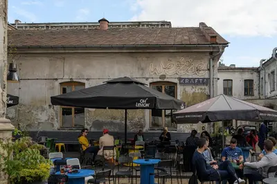 a group of people sitting at tables in front of a building at Native Apartments Rajska 3 in Kraków