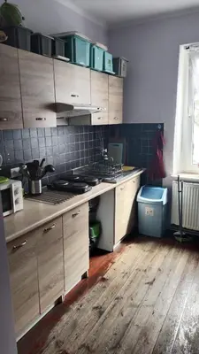 a kitchen with wooden cabinets and a wooden floor at Willa Retro Hostel & Garden in Kraków