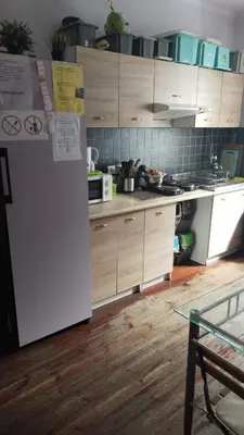 a kitchen with a white refrigerator and wooden cabinets at Willa Retro Hostel & Garden in Kraków
