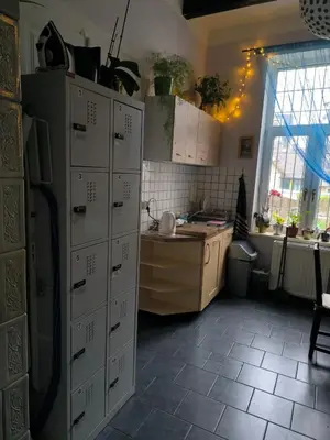 a kitchen with a bunch of cabinets and a table at Willa Retro Hostel & Garden in Kraków