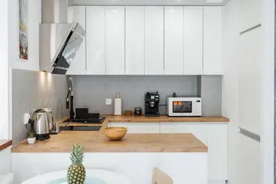 a kitchen with white cabinets and a pineapple on a counter at Harmo Old Town with Spacious Sunny Terrace in Kraków
