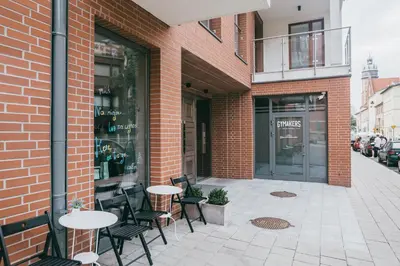 a brick building with tables and chairs on a sidewalk at Harmo Old Town with Spacious Sunny Terrace in Kraków