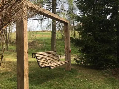 a wooden swing in a park with a tree at Apartament 212 in Klikuszowa