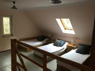 a attic room with two beds and a window at Osada Babiogórska - domki gościnne in Zawoja
