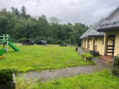 a yard with a playground next to a building at Osada Babiogórska - domki gościnne in Zawoja