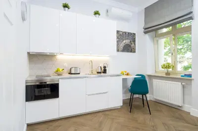 a kitchen with white cabinets and a blue chair at Old Town Residence at Topolowa in Kraków