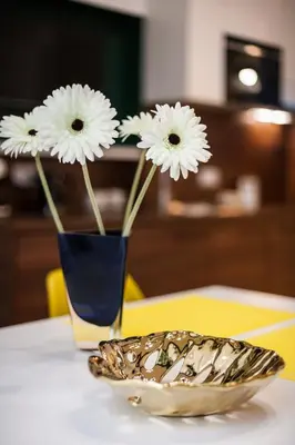 two white flowers in a blue vase on a table at VINTAGE SENACKA APARTAMENTS in Kraków