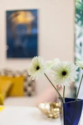 a blue vase filled with white flowers on a table at VINTAGE SENACKA APARTAMENTS in Kraków