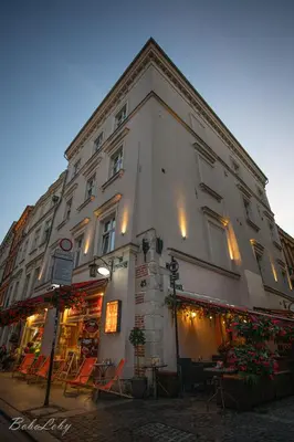 a large white building with a store on a street at VINTAGE SENACKA APARTAMENTS in Kraków
