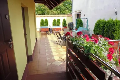 a balcony with red flowers and a table and chairs at Mączne Skały in Biały Kościół