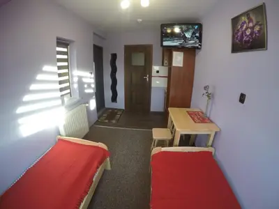 a room with two beds and a table and a refrigerator at Mączne Skały in Biały Kościół