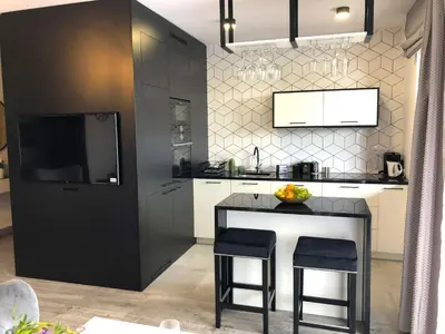 a kitchen with a bar with two stools and a television at Glamour Apartment with big, private terrace in Kraków