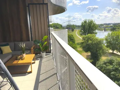 a balcony with a bench and a view of a river at Glamour Apartment with big, private terrace in Kraków