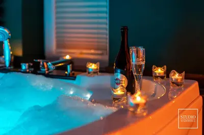 a hot tub with a bottle of wine and glasses at Exclusive Apartment Centrum in Wadowice