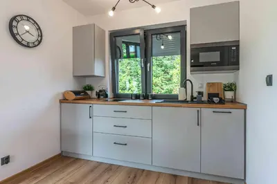 a kitchen with white cabinets and a clock on the wall at Dworek na Zakręcie - noclegi Zator in Zator