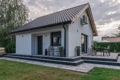 a small white house with a table and chairs at Dworek na Zakręcie - noclegi Zator in Zator