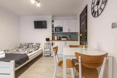 a small apartment with a bed and a table and chairs at Dworek na Zakręcie - noclegi Zator in Zator