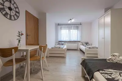 a bedroom with a table and a dining room with a clock at Dworek na Zakręcie - noclegi Zator in Zator