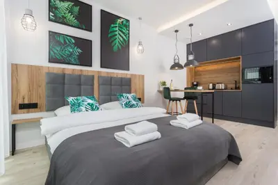 a bedroom with a large bed and a kitchen at City of the Kings - City Point Green - Rajska 3 in Kraków