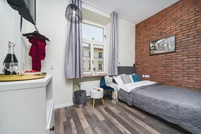 a bedroom with a bed and a brick wall at Liv Apartments Old Town in Kraków