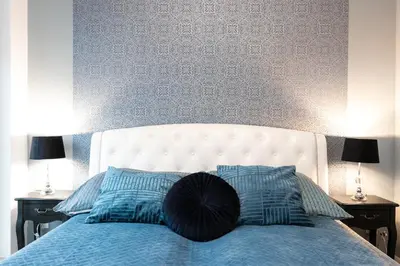 a bed with a white headboard and two blue pillows at Rayska Loft Krakow by AS Apartments in Kraków