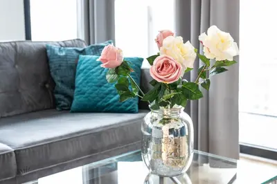 a vase filled with pink and white roses on a glass table at Rayska Loft Krakow by AS Apartments in Kraków