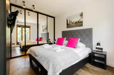 a bedroom with a large bed with pink pillows at Central Kazimierz Apartment with balcony in Kraków