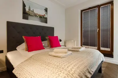 a bedroom with a large bed with two red pillows at Central Kazimierz Apartment with balcony in Kraków