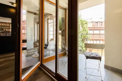 a room with glass doors and a chair on a balcony at Central Kazimierz Apartment with balcony in Kraków