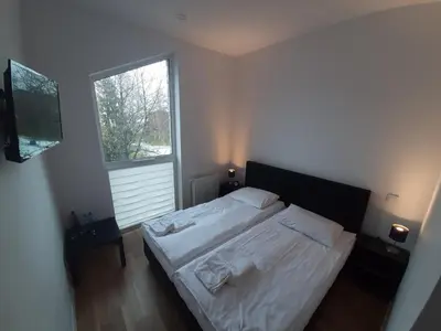a bedroom with a bed with white sheets and a window at Apartamenty Szlachecki Dwór in Pobiednik Wielki