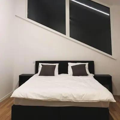 a bedroom with a white bed with a black headboard at Apartamenty Szlachecki Dwór in Pobiednik Wielki