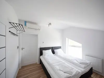 a white bedroom with a bed and a door at Apartamenty Szlachecki Dwór in Pobiednik Wielki