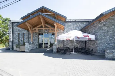 a stone building with an umbrella and tables and chairs at Apartamenty Szlachecki Dwór in Pobiednik Wielki