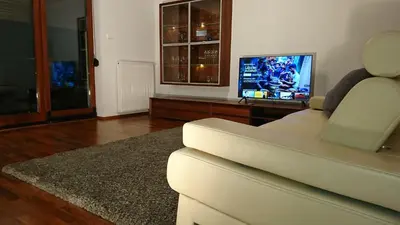 a living room with a white couch and a tv at Quiet and spacious apartment with garage option in Kraków
