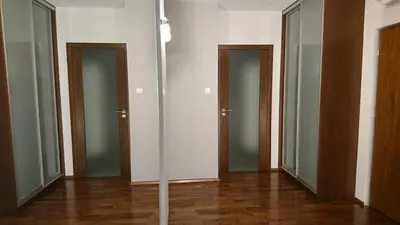 an empty room with three doors and wooden floors at Quiet and spacious apartment with garage option in Kraków