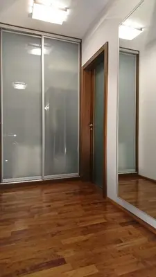 an empty room with glass doors and wooden floors at Quiet and spacious apartment with garage option in Kraków