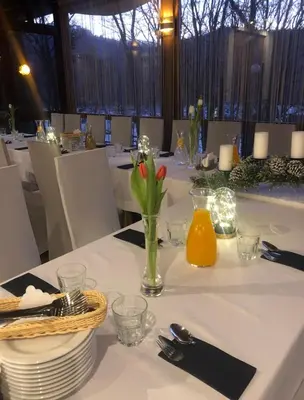 a table with plates and a vase of flowers on it at Ośrodek Szkoleniowo Wypoczynkowy ROŻNÓW in Rożnów