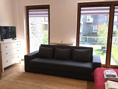a living room with a couch and a large window at Apartment Novum Rakowicka Street in Kraków