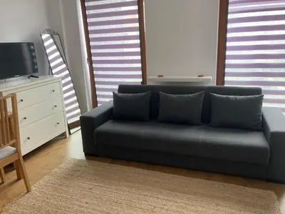 a living room with a blue couch and a tv at Apartment Novum Rakowicka Street in Kraków