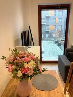 a vase of flowers on a table in a living room at Apartment Novum Rakowicka Street in Kraków