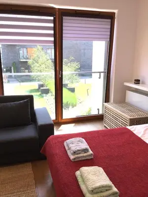 a bedroom with a bed and a couch and a large window at Apartment Novum Rakowicka Street in Kraków