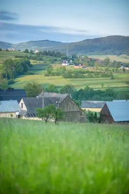 a view of a farm with buildings and a field at Domki Zagroda Domek z bala z basenem & sauna & balia z hydromasażem in Słopnice