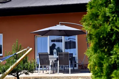 a table with chairs and an umbrella in front of a house at Apartament U Grazi in Spytkowice