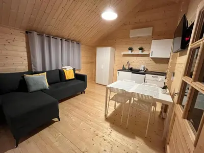 a living room with a black couch and a table at Słoneczny Ogród domki letniskowe Zator in Zator