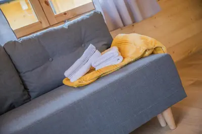a blue couch with a blanket and two white towels at Słoneczny Ogród domki letniskowe Zator in Zator