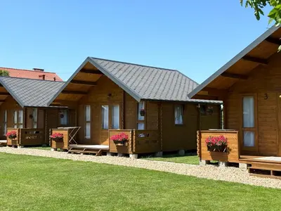 a row of cottages with benches in the grass at Słoneczny Ogród domki letniskowe Zator in Zator
