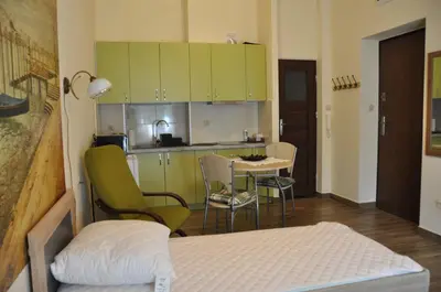 a room with a bed and a kitchen with green cabinets at Wenecja 4A by Homeprime in Kraków