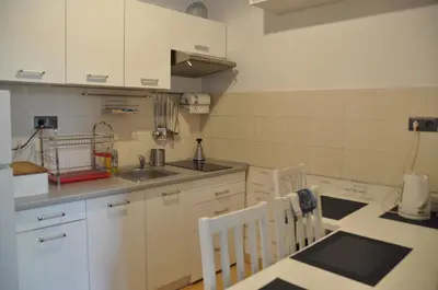 a kitchen with white cabinets and a table and chairs at aleja Krasińskiego 30 by Homeprime in Kraków
